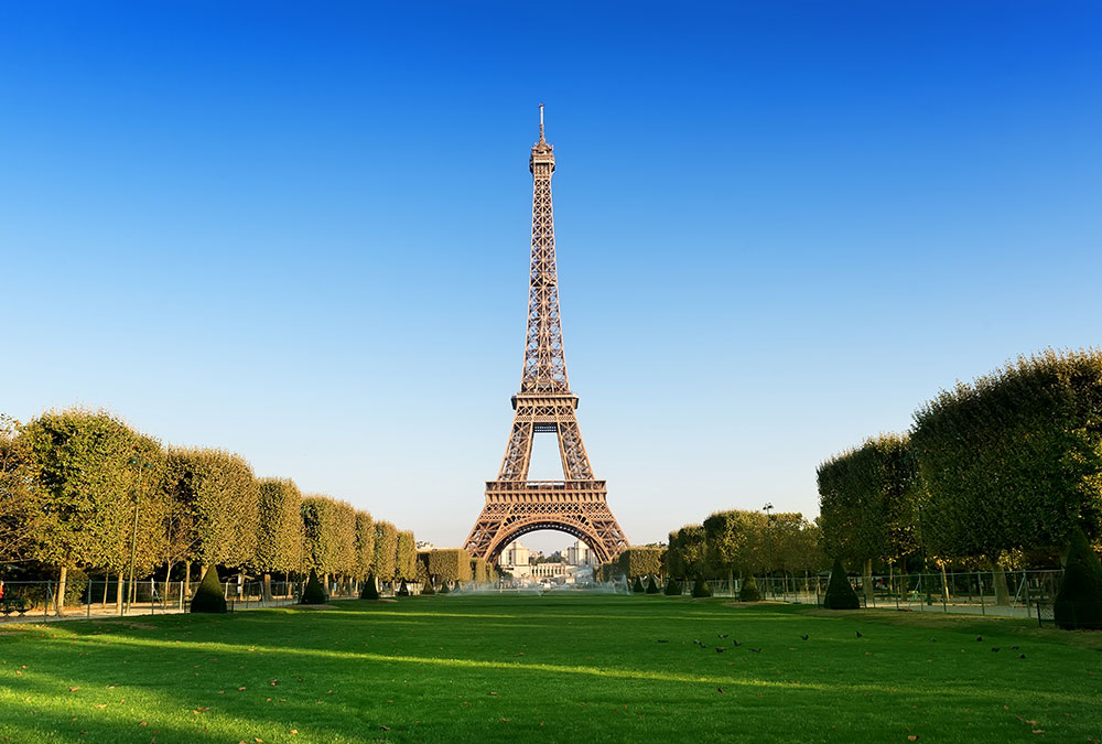 Vue du Champ de Mars avec la Tour Eiffel en arrière-plan, par un jour ensoleillé.