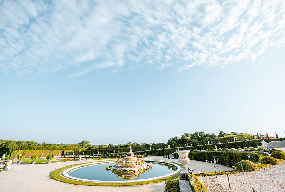 Vue panoramique du Château de Versailles avec ses jardins à la française.